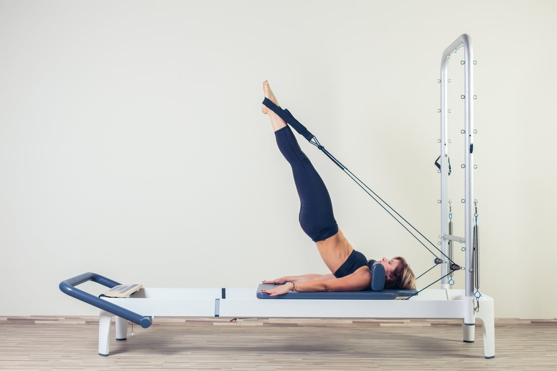 Pilates reformer workout exercises woman brunette at gym indoor